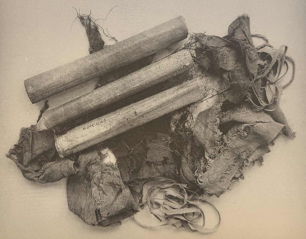 Photographie en sépia représentant 3 paquets de papyrus en haut à gauche.