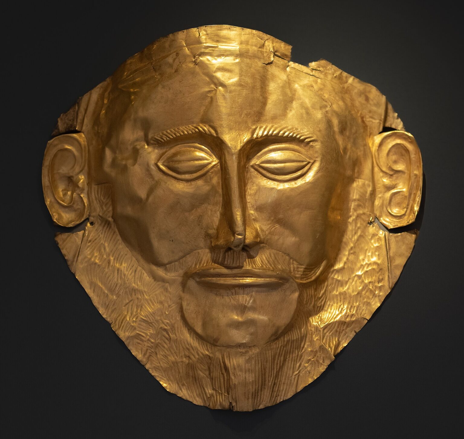 Masque mortuaire en or repoussé retrouvé dans la tombe V du cercle A à Mycènes. Vers 1600-1500 avant J.-C. Athènes, Musée national archéologique d'Athènes - Wikipedia Commons